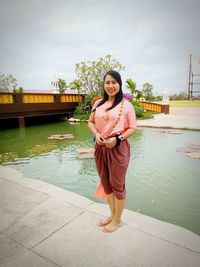 Portrait of smiling young woman standing against water