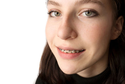 Close-up portrait of smiling young woman against white background