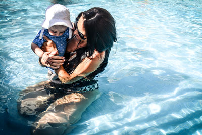 High angle view of mother with toddler son in swimming pool