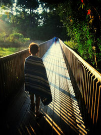 Rear view of  boy walking on footbridge