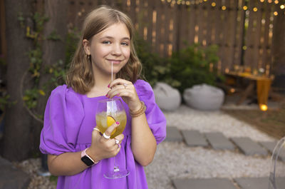 Portrait of young woman drinking wine in city