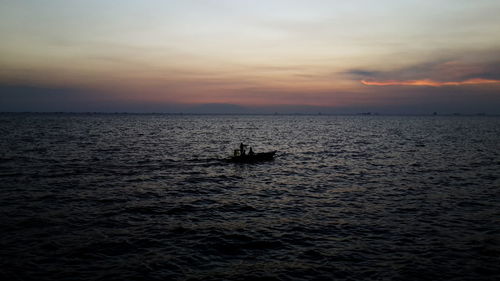 Boats in sea at sunset