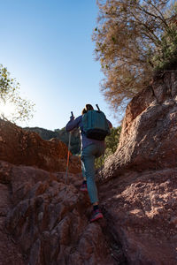 Woman climbs the mountain in the garraf natural park, supported by hiking sticks.