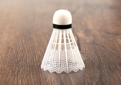 White plastic badminton shuttlecock vertically on a wooden background.