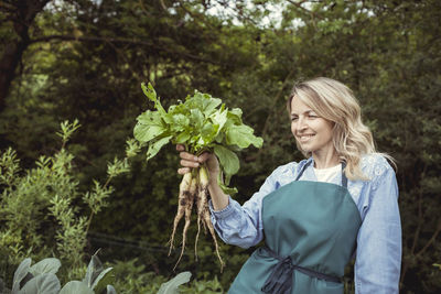 Young woman smiling while holding plants