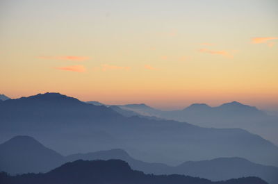 Scenic view of mountains in foggy weather during sunrise