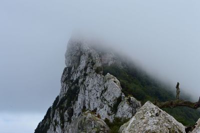 Low angle view of rocky mountain covered with clouds