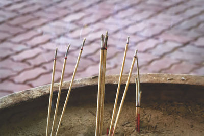 Close-up of incense sticks in container on footpath