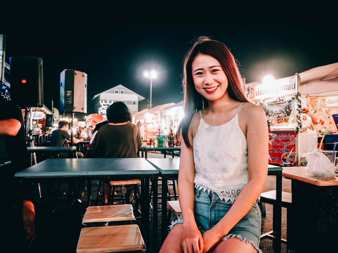 real people, lifestyles, looking at camera, night, smiling, young adult, one person, women, portrait, young women, leisure activity, standing, happiness, illuminated, casual clothing, incidental people, emotion, front view, waist up, hairstyle