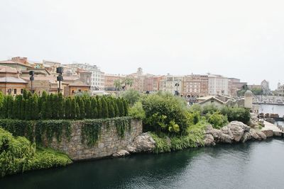 Buildings by river against clear sky