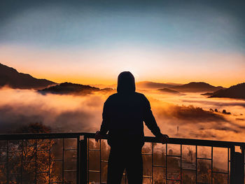 City above of the clouds and a wonderful sunrise surrounded by fog and muntains.and man against  sun