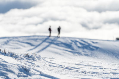 People on snow covered land against sky