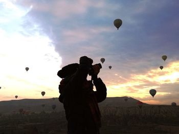 Silhouette of hot air balloons against sky during sunset