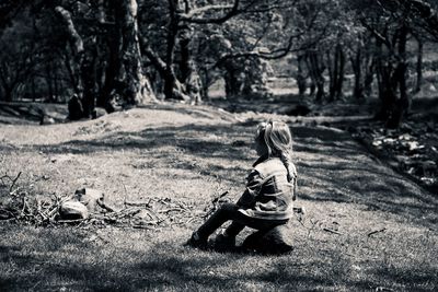 Rear view of woman sitting on field