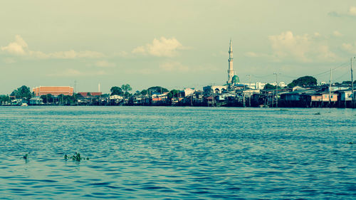 Scenic view of sea by buildings against sky