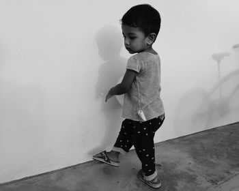 Full length of cute boy standing against wall