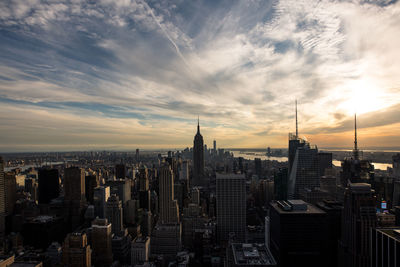 Aerial view of buildings in city against cloudy sky