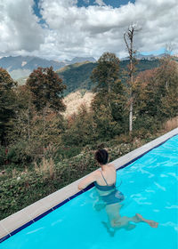 Woman in swimming pool against trees