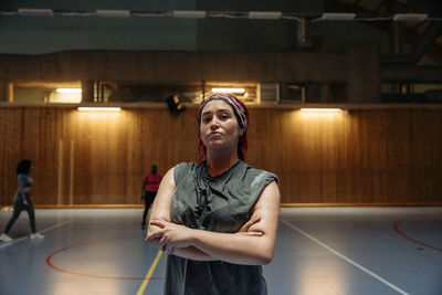 Portrait of confident female athlete with arms crossed at sports court