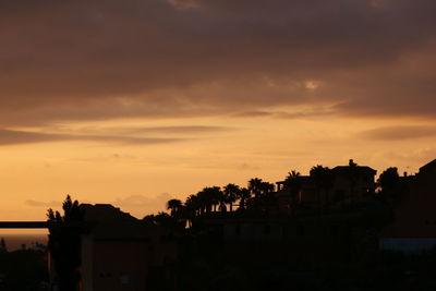 Low angle view of silhouette houses against sky during sunset
