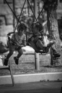 Rear view of children on swing at playground