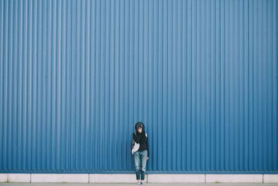 Full length of woman standing against wall