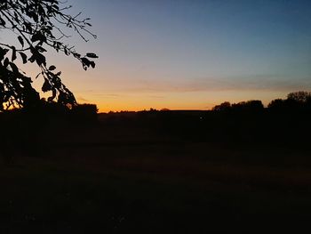 Scenic view of silhouette field against sky at sunset