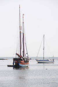 Sailboats moored on sea against sky