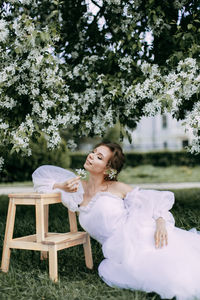 A beautiful delicate woman bride in a wedding dress walks alone in a blooming spring outdoor park