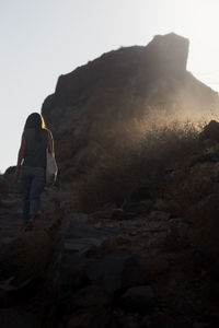 Rear view of woman walking on mountain against clear sky