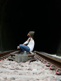 Full length of woman sitting on railroad track by tunnel