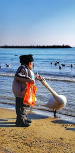 Side view of man on beach against clear sky