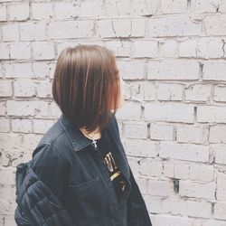 Full length of woman standing against brick wall