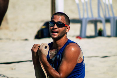 Portrait of young man wearing sunglasses standing at beach