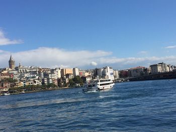 Sea by buildings in city against sky