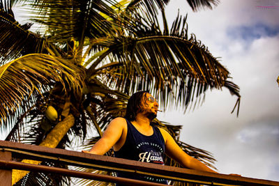 Low angle view of man against palm tree