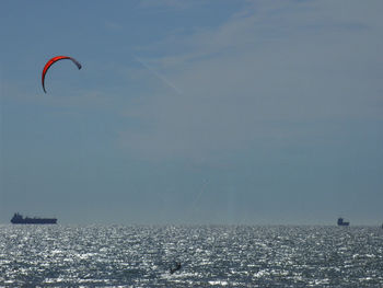 Person paragliding over sea against clear sky
