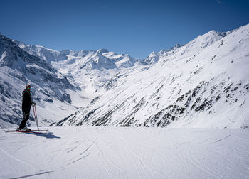 Young man with ski makes pose in mountains behind