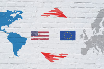 Close-up of american and european union flag on white brick wall