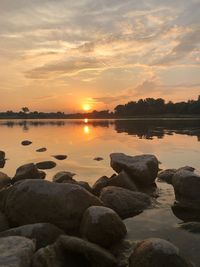 Scenic view of rocks in lake against sky during sunset