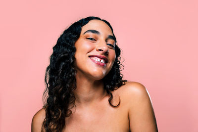 Portrait of young woman against pink background