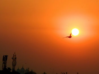 Silhouette airplane flying against orange sky
