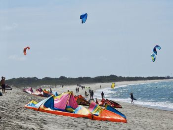 People paragliding over beach against sky