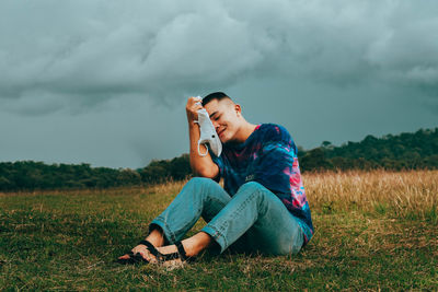 Man using mobile phone while sitting on field