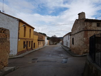 Road amidst houses against sky in city