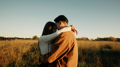 Romantic couple hugging in a field at sunset light