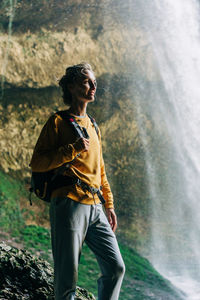 Woman hiker with a backpack in a mountain canyon near a large waterfall.