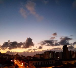 Illuminated buildings in city against sky during sunset