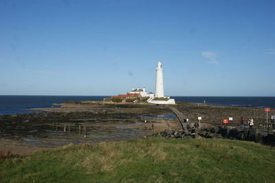 Lighthouse by sea against sky