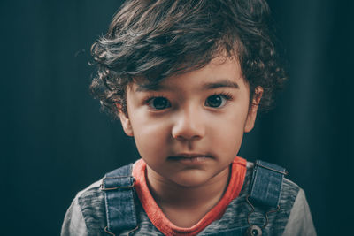 Portrait of cute boy against black background